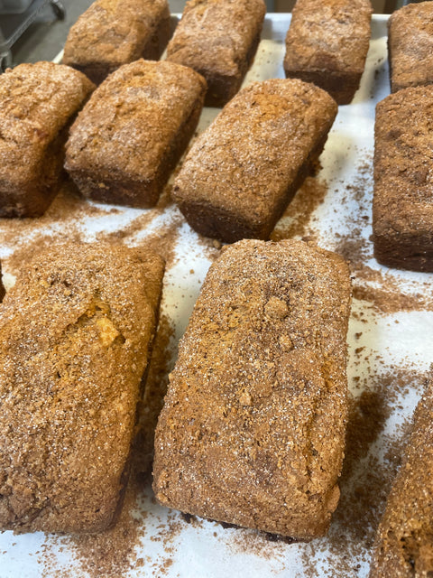 Several loaves of warm, freshly baked apple cinnamon bread with cinnamon swirls on a baking sheet