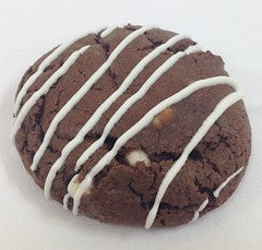 Single double chocolate chip cookie with white chocolate chips and white chocolate drizzle on white background